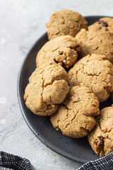 Homemade vegan cookies with nuts and raisin on a ceramic plate, grey concrete background. 