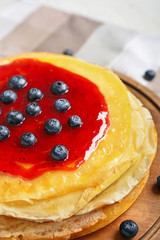 Board with tasty blini and berries on table, closeup
