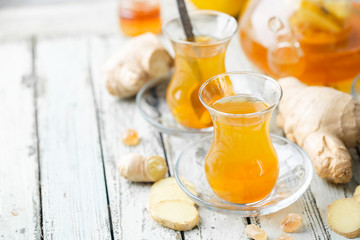 Ginger tea in a glass cup with lemon and mint on light background