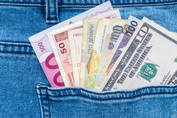 Multi currency banknotes in back pocket of blue jeans. Business concept