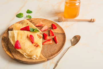 Tasty blini with berries and honey on table