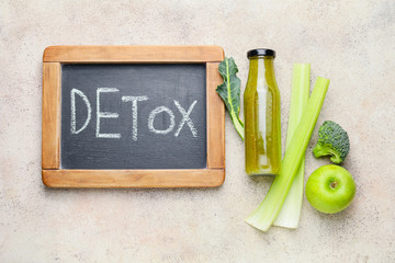 Chalkboard with text DETOX, healthy smoothie and ingredients on table