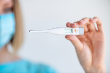 Female doctor or nurse holds a electronic thermometer for measuring temperature