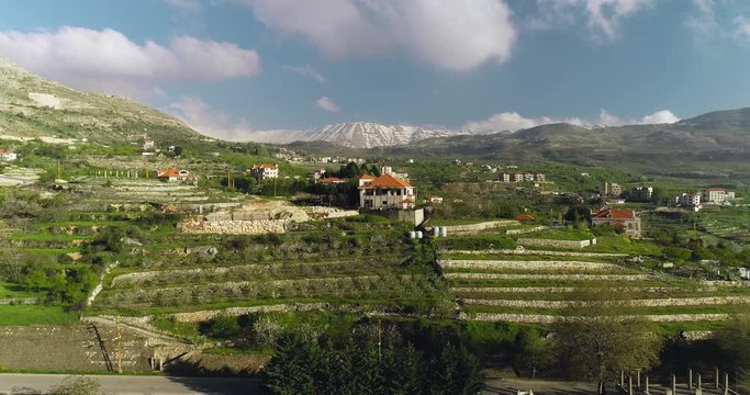 aerial pull back of  a house on hill top between agricultural mountain ranges, ehden Lebanon