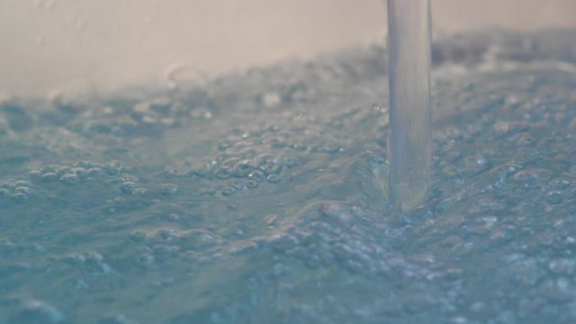 Close-up of a stream of water hitting the surface while running a warm bath.
