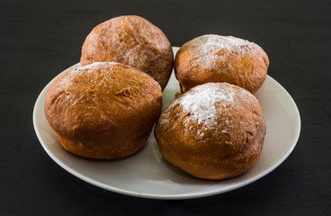 Ukrainian donuts in a white plate on a black background.