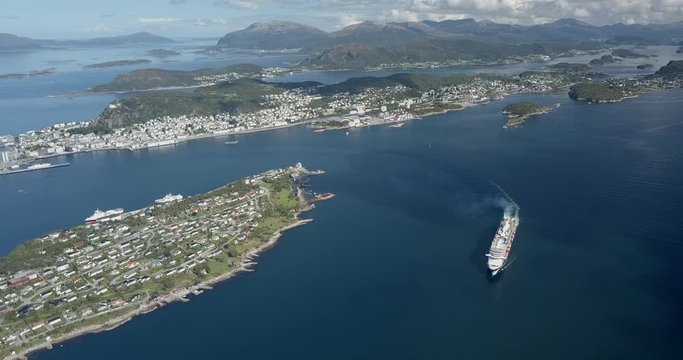 Extremely cinematic, high altitude drone footage of a luxurious cruise ship sailing in a fjord next to Alesund, the most beautiful Art Nouveau (Jugendstil) town in Norway.