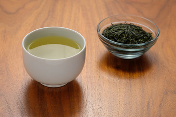 Tasse Grüntee und Schale Teeblätter grün