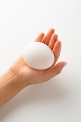 Fototapeta na wymiar 卵を持つ片手　縦位置