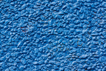 Background texture of small pebbles painted with blue paint. Stones fastened with a solution on a wall at home. Horizontal.