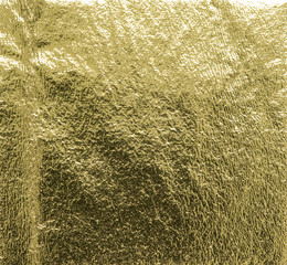 Real gold foil texture background with light reflections.