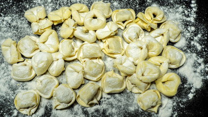 Delicious tortellini a ring-shaped pasta from Italy. Traditionally they are stuffed with a mix of meat, parmigiano reggiano cheese, egg and nutmeg. Black background