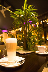 2 cups of coffee on the table in romantic cafe with palm tree and lights,latte and espresso 
