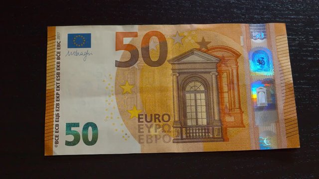 Slow pan over fifty euro bill on black background