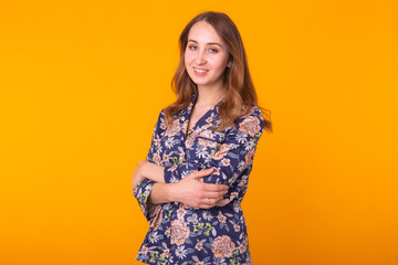 Excited young woman with curly hair in home wear pajama, widely smiling having fun. Isolated on yellow background.