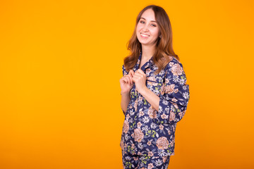 Obraz premium Cute and cheerful woman in home wear pajama studio lifestyle yellow background emotions. Copy space.