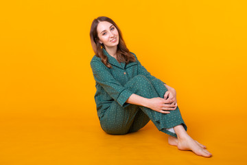 Young girl posing in pajamas on yellow background. Relax good mood, lifestyle and sleepwear concept.