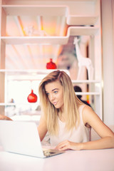 a beautiful young serious businesswoman is   working   on a laptop in a cosy cafe  in the morning