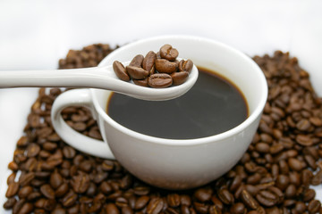 white coffee cup, spoon and roasted coffee beans that isolated on white background. top view.
