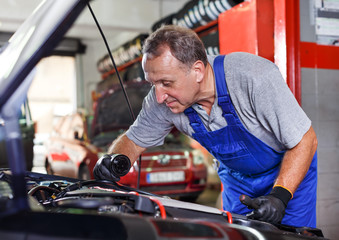 Car mechanician changing motor oil in vehicle