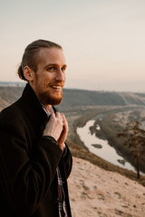 long haired bearded guy with guitar standing in the sunset