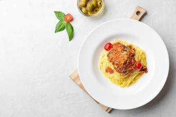 Italian pasta in a white plate with tomato sauce, olive, concrete. Top view