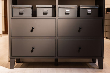 Closeup of a gray chest of drawers. A variant of simple furniture without decor and design in the interior.