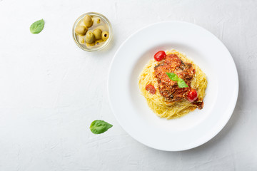 Italian pasta in a white plate with tomato sauce, basil, olive, concrete. Top view