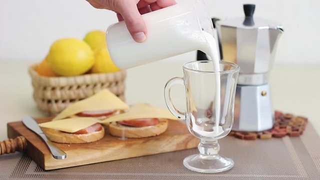 Hand Pouring Milk Into Tall Glass, Preparing To Make Latte Coffee In The Home Kitchen