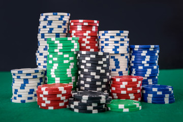 Gambling theme. Colorful playing chips in stacks on green table close up