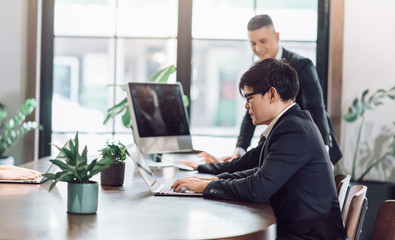 Adult Asian Business Man Working with Laptop Computer in Corporate Office Co-Working Space