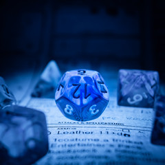 Transparent poly dice D12 illuminated from below with soft blue light on a dungeons and dragons...