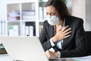 Executive wearing mask holding chest at the office