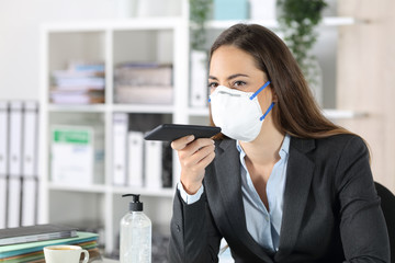 Executive with mask using voice recognition on phone