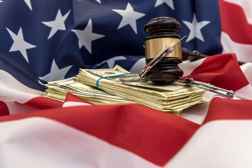 Judge's gavel with handcuffs and dollar bills above flag od america. law or crime concept