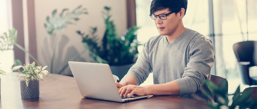 Handsome Asian Man Using Laptop Computer Connect With High Speed Internet 5G Wireless Connection Technology Work From Home ,  E-Learning , Online Shopping , E-Commerce , Freelance Concept