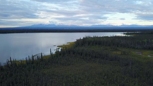 Slow sweeping aerial panorama reflections on a forest lined Alaskan lake near Denali National Park