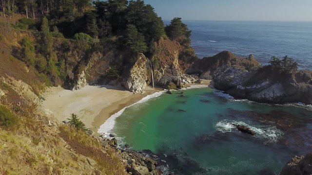 Gentle ocean waves washing up on the pristine beach of McWay Cove Big Sur, California Slow aerial zoom out