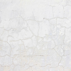 the background of the cracked white wall of the house is old covered with plaster and the paint is peeling from time. Very old house. cracks in the wall