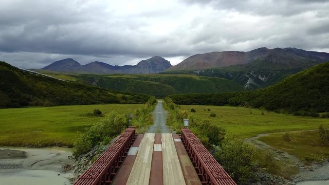 Breathtaking panoramic aerial push crossing a modular steel and wooden bridge near Denali National Park, Alaska
