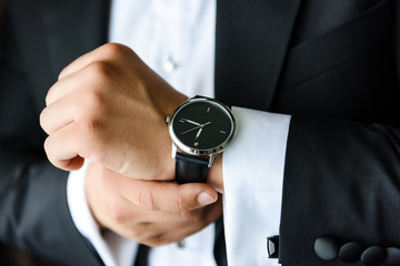 Businessman hand adjusting the strap of his watch .