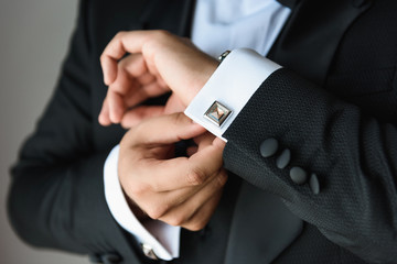 Businessman adjusts his white shirt button .