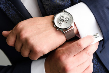Businessman adjusts his white shirt cuff .