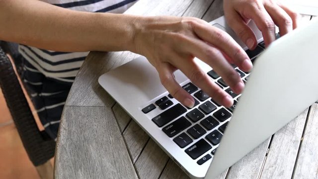 Woman typing on her computer laptop. Home setting. High angle. Closeup.