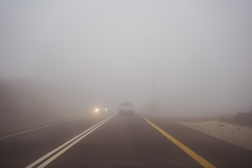 Car and truck driving in dense fog in the mountains near Abha