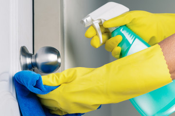 Cleaning door knob with alcohol spray for Covid-19 Coronavirus prevention