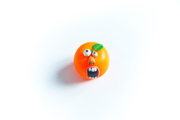 Toy orange with eyes and mouth of plasticine. Conceptual photo.