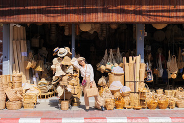 an Asian girl standing in the front of traditional Thai style Rattan bag handmade at Chiangmai thailand