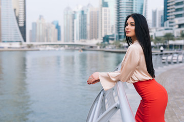 Professional business woman in office attire on a boardwalk with skyscrappers background