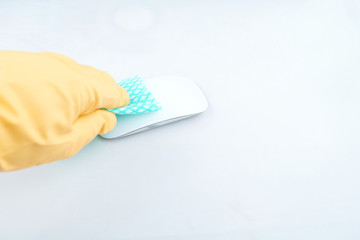 Photo of hand wearing yellow gloves disinfecting a digital mouse